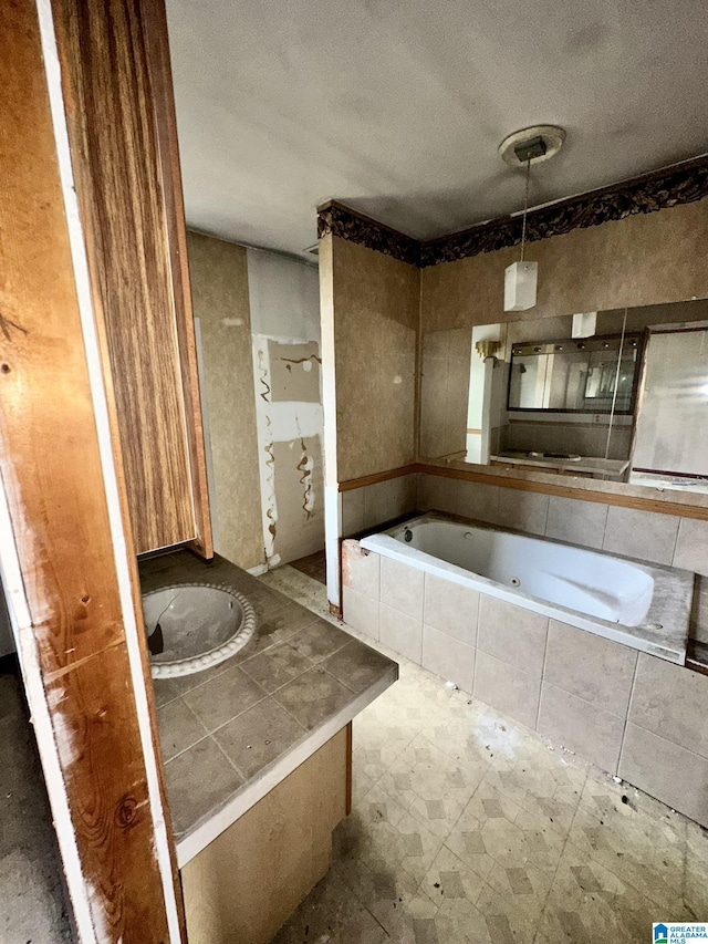 bathroom featuring tiled tub, vanity, and a textured ceiling