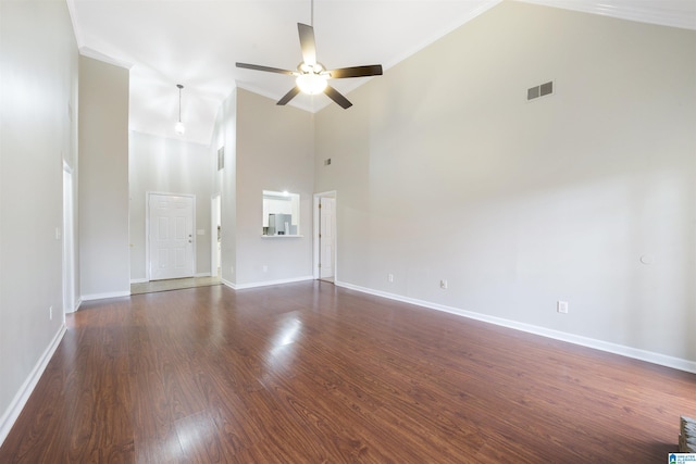 unfurnished living room featuring ceiling fan, dark wood-type flooring, a high ceiling, and crown molding