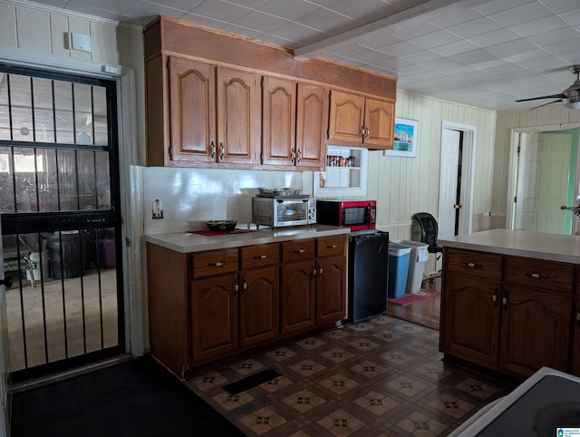 kitchen with fridge, wood walls, and ceiling fan