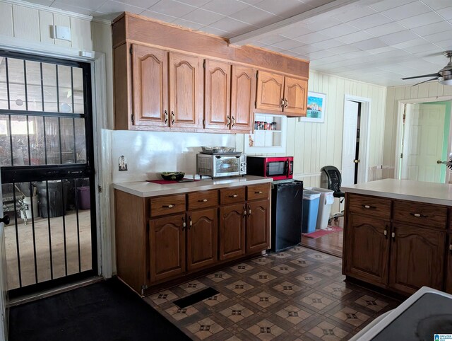 kitchen featuring ceiling fan, wood walls, and fridge