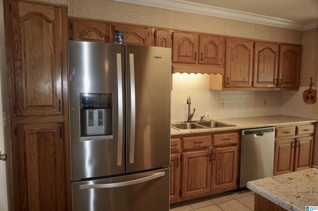kitchen featuring appliances with stainless steel finishes, light tile patterned floors, decorative backsplash, ornamental molding, and sink