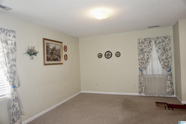 carpeted spare room with a textured ceiling