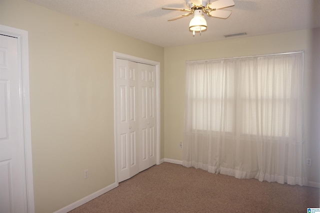 unfurnished bedroom featuring ceiling fan, carpet flooring, and a textured ceiling