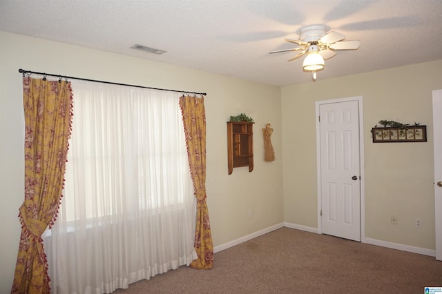 unfurnished room featuring ceiling fan, carpet floors, and a textured ceiling