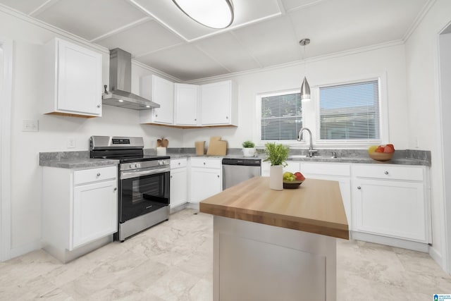 kitchen featuring appliances with stainless steel finishes, white cabinets, decorative light fixtures, and wall chimney range hood