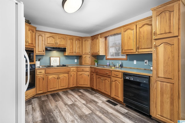 kitchen with dark wood-style floors, light countertops, a sink, ventilation hood, and black appliances