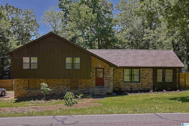 tri-level home featuring board and batten siding, brick siding, and a front lawn