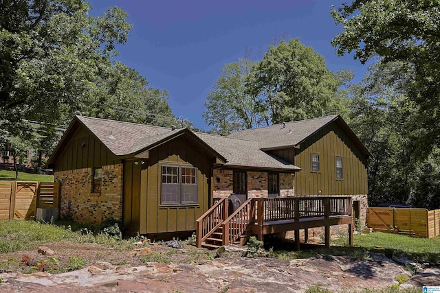 view of front facade with brick siding, board and batten siding, and fence