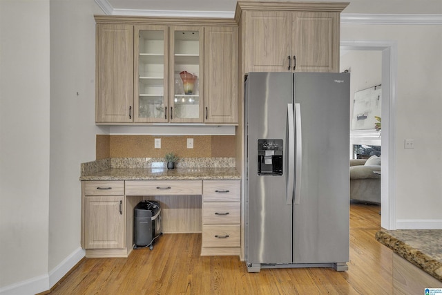 kitchen with light brown cabinetry, light stone counters, glass insert cabinets, and stainless steel fridge with ice dispenser