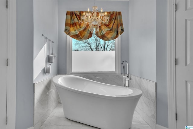 full bath featuring a wainscoted wall, a soaking tub, tile walls, and an inviting chandelier