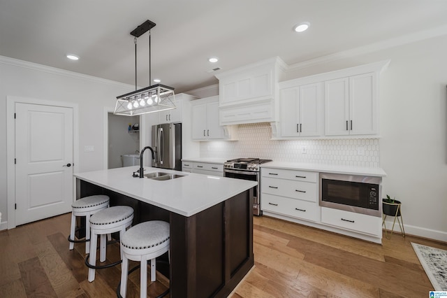 kitchen with stainless steel appliances, a sink, tasteful backsplash, an island with sink, and crown molding