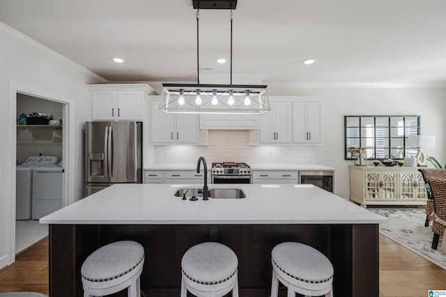 kitchen with tasteful backsplash, appliances with stainless steel finishes, crown molding, separate washer and dryer, and a sink