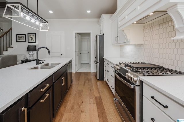 kitchen featuring stainless steel appliances, light countertops, premium range hood, white cabinetry, and a sink