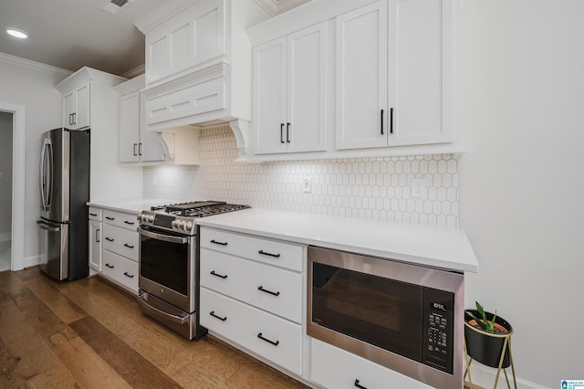 kitchen featuring dark wood-type flooring, white cabinets, light countertops, appliances with stainless steel finishes, and backsplash