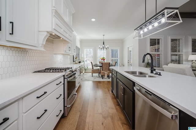 kitchen with decorative backsplash, appliances with stainless steel finishes, light countertops, white cabinetry, and a sink