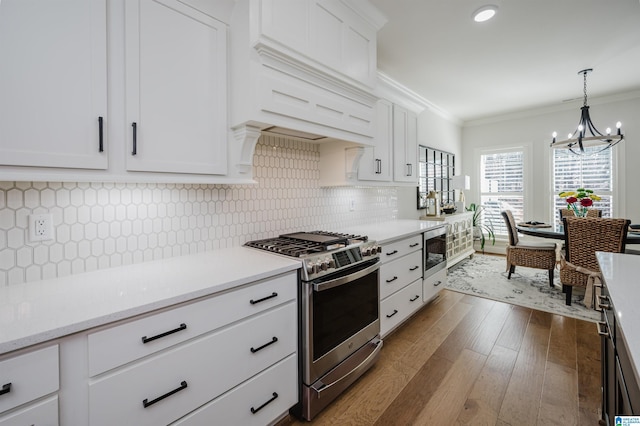 kitchen with dark wood-style flooring, light countertops, ornamental molding, appliances with stainless steel finishes, and custom exhaust hood