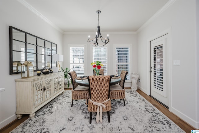 dining area featuring baseboards, ornamental molding, wood finished floors, and a notable chandelier