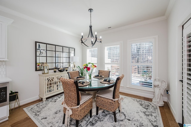 dining area with a notable chandelier, wood finished floors, visible vents, and crown molding