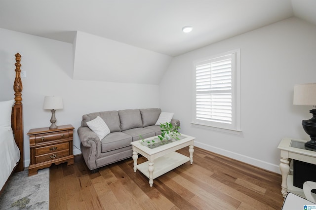 living room featuring light wood-style floors, vaulted ceiling, and baseboards