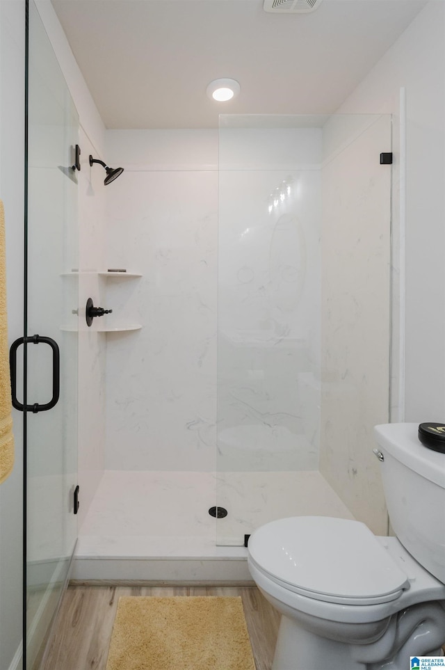 full bathroom featuring a stall shower, visible vents, toilet, and wood finished floors