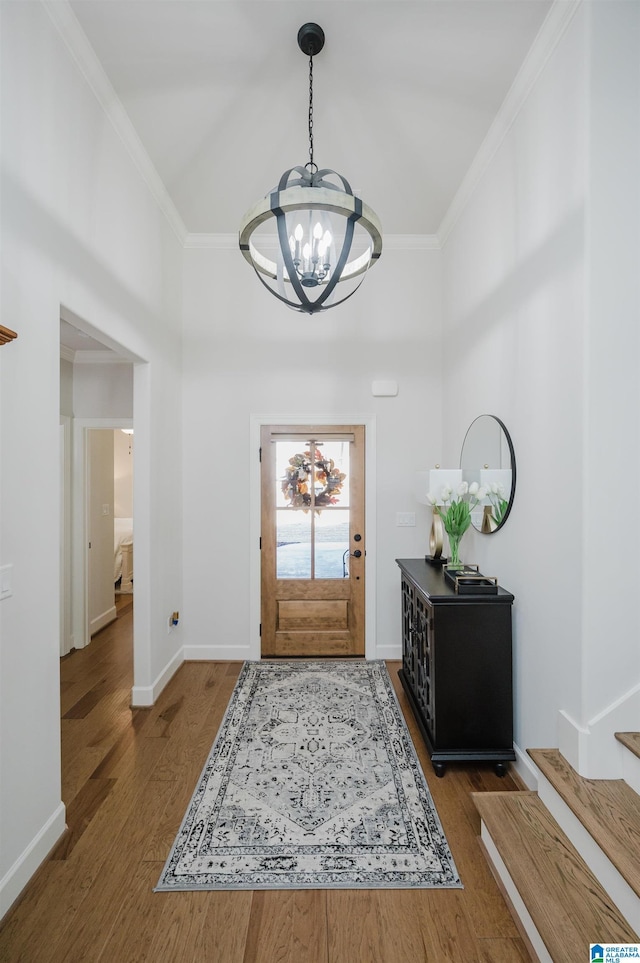 foyer with a notable chandelier, ornamental molding, and wood finished floors