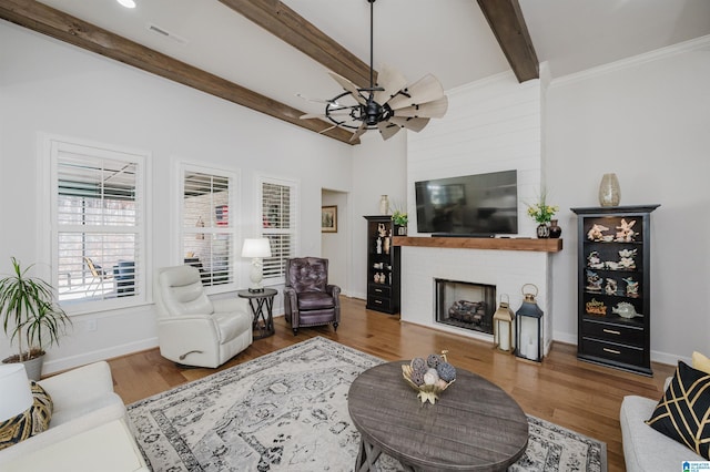 living area featuring ceiling fan, a fireplace, wood finished floors, baseboards, and beamed ceiling