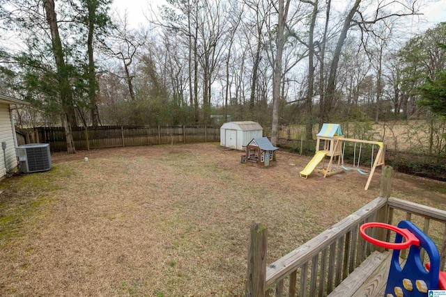 view of yard with central AC unit, a playground, an outdoor structure, fence, and a storage unit