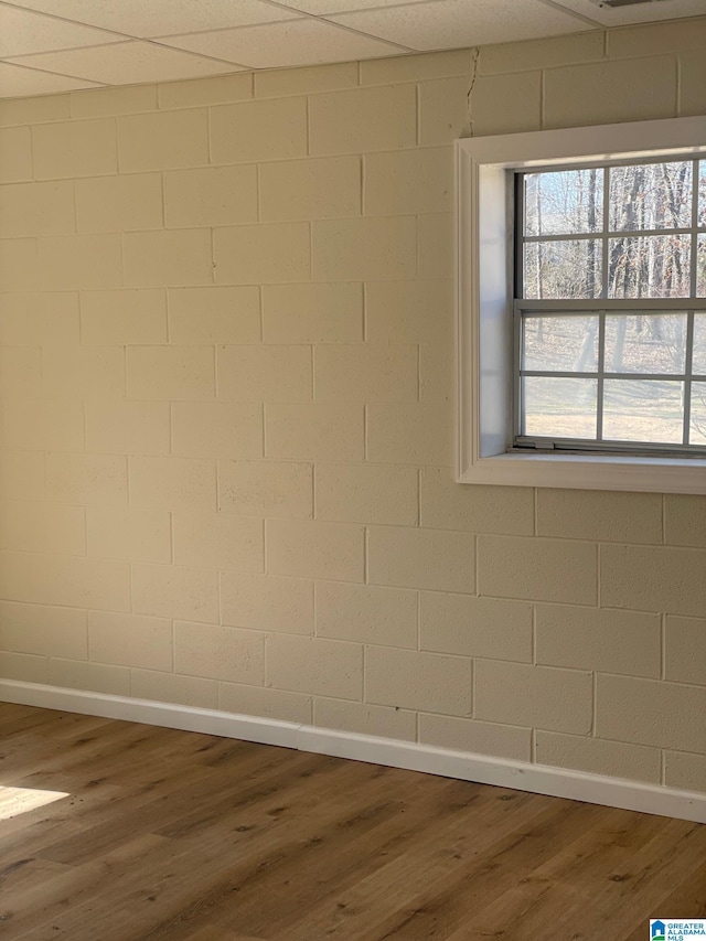spare room featuring wood finished floors, concrete block wall, and baseboards