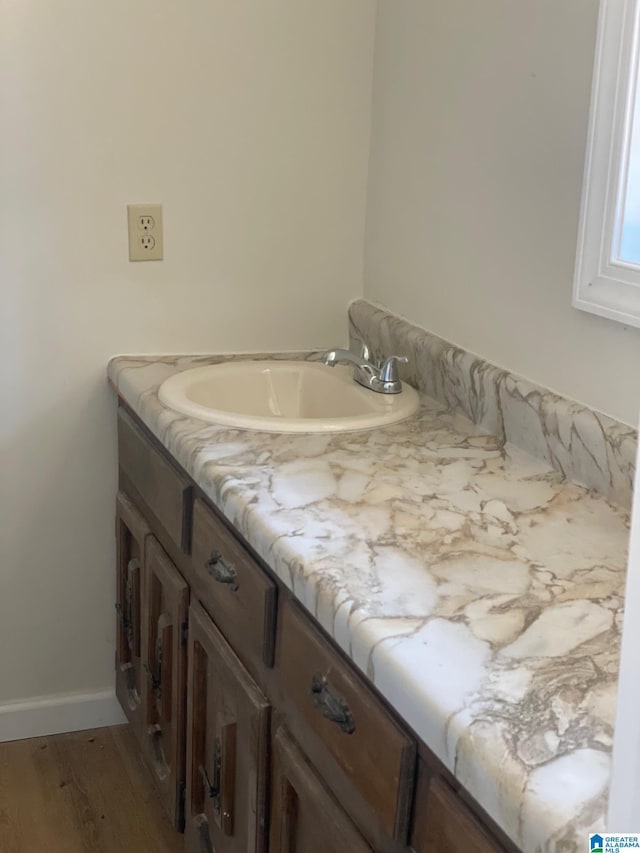 bathroom featuring vanity, wood finished floors, and baseboards