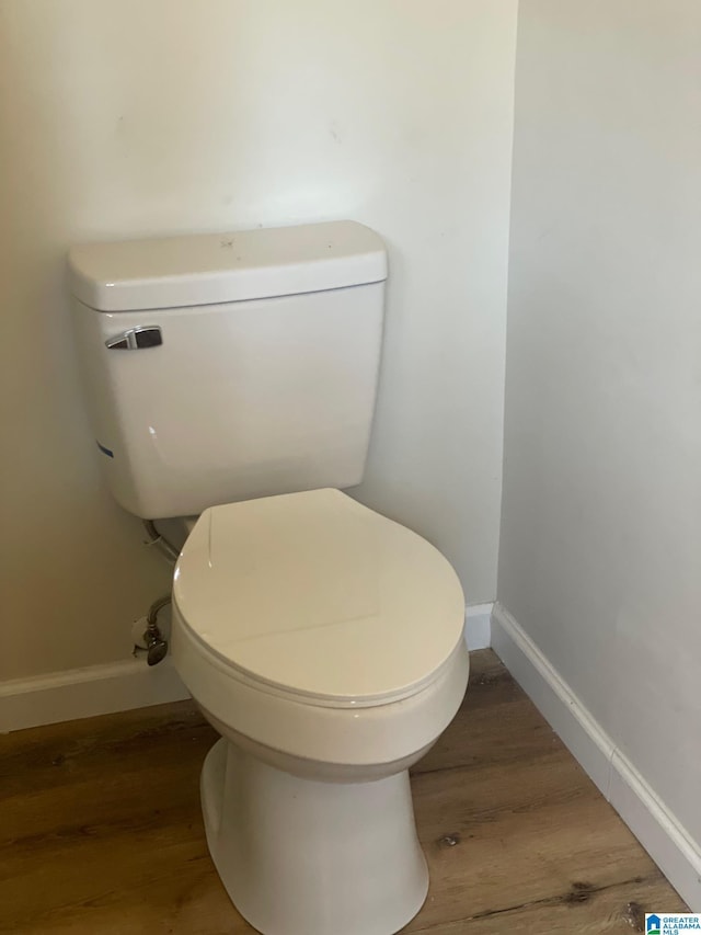 bathroom featuring toilet, wood finished floors, and baseboards