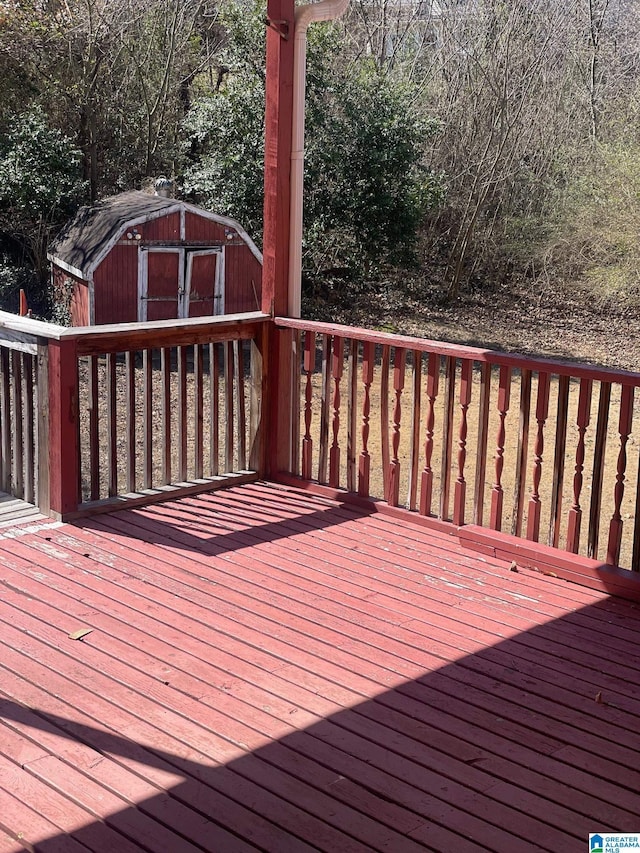 wooden terrace featuring an outdoor structure and a storage unit