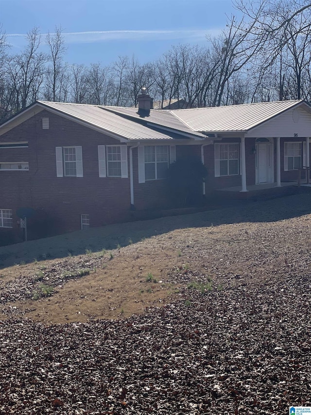 view of property exterior with a chimney, metal roof, and a standing seam roof