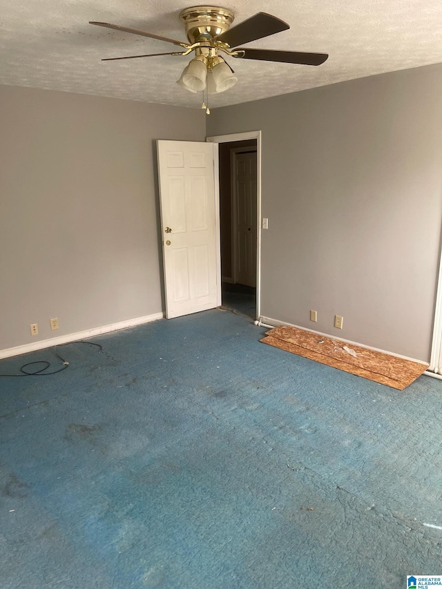 carpeted spare room with baseboards, a ceiling fan, and a textured ceiling