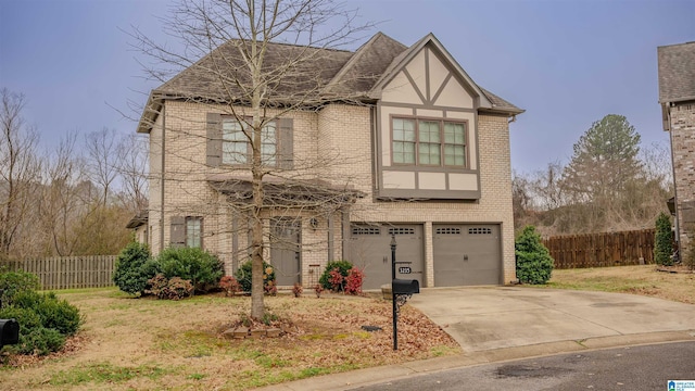 view of front of house with a garage, driveway, brick siding, and fence