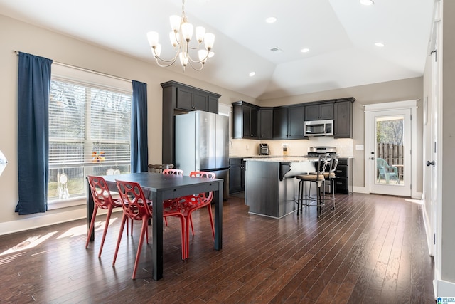 dining area featuring dark wood-style flooring, lofted ceiling, recessed lighting, an inviting chandelier, and baseboards