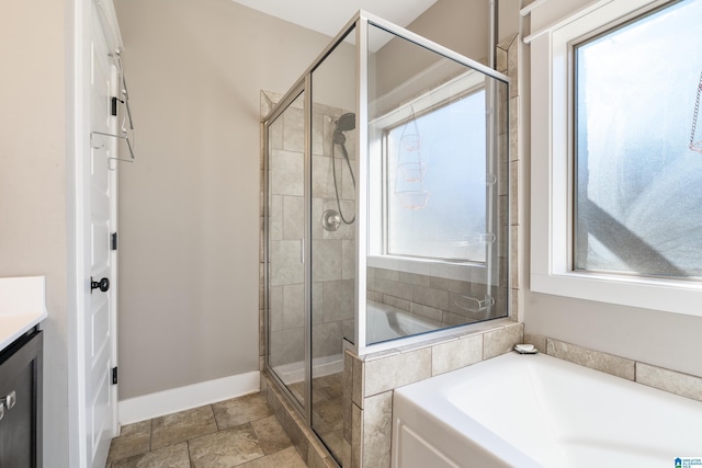 bathroom with a bath, a shower stall, vanity, and baseboards