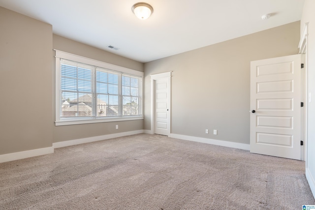 carpeted spare room with visible vents and baseboards