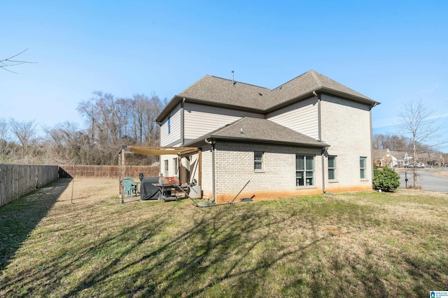 rear view of house with a patio, a fenced backyard, brick siding, a yard, and roof with shingles