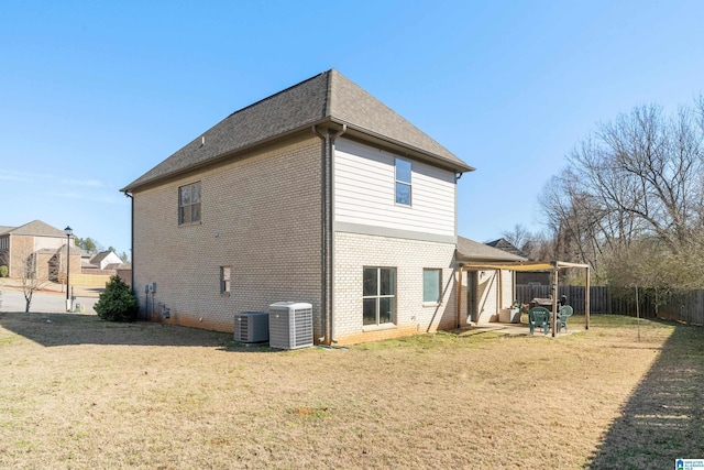 rear view of property with fence private yard, brick siding, a yard, and central air condition unit