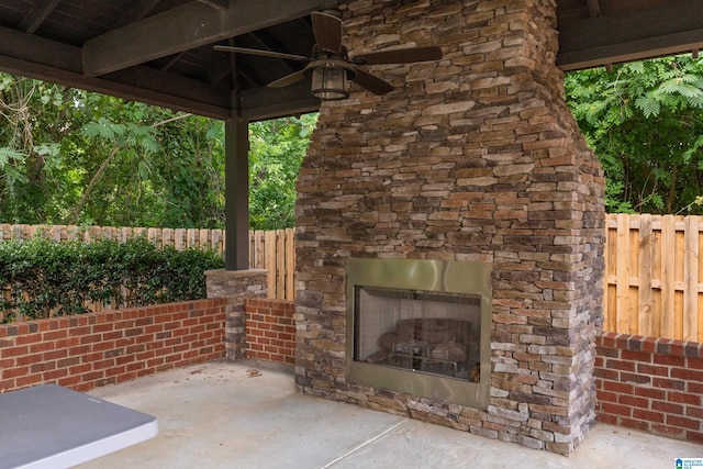 view of patio / terrace with ceiling fan, fence, and an outdoor stone fireplace