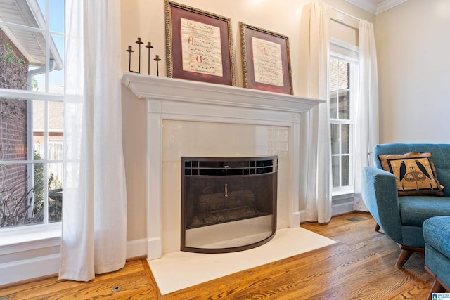 sitting room featuring a fireplace with flush hearth, a wealth of natural light, and wood finished floors