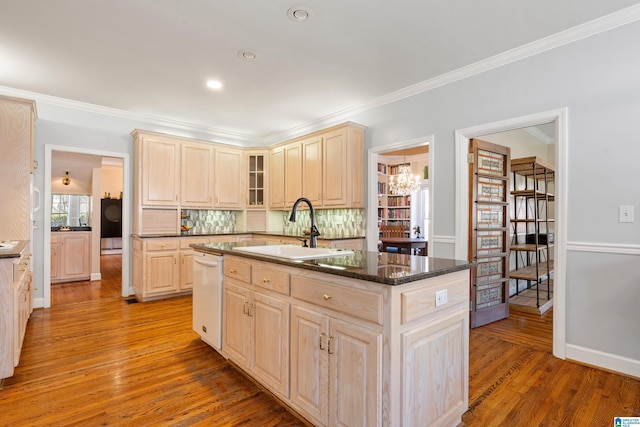 kitchen with a center island with sink, wood finished floors, white dishwasher, light brown cabinets, and a sink