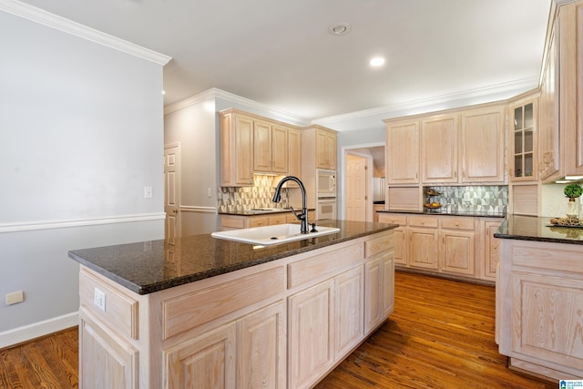 kitchen with light brown cabinetry, white appliances, dark wood-style flooring, and a sink