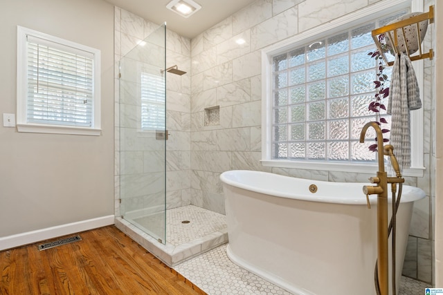 full bathroom with visible vents, baseboards, wood finished floors, a freestanding tub, and a shower stall