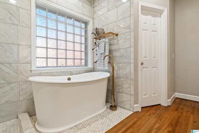 full bathroom featuring a freestanding bath, tile walls, and wood finished floors