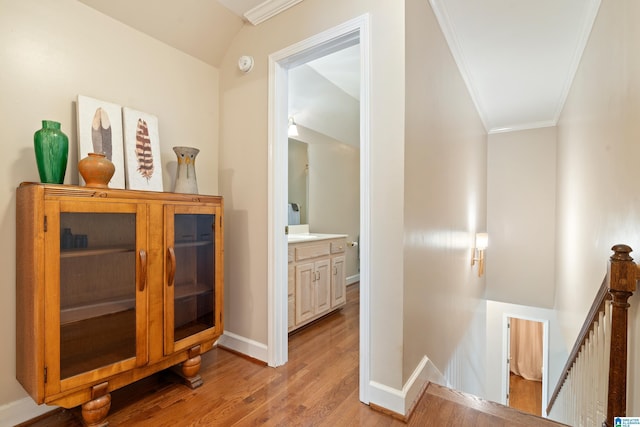 corridor with baseboards, light wood-style flooring, an upstairs landing, and crown molding