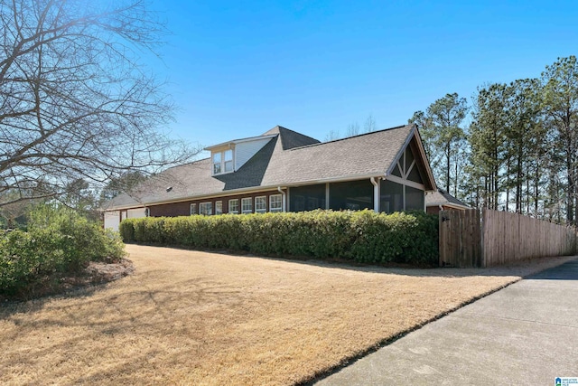 view of side of property featuring a shingled roof, a sunroom, and fence