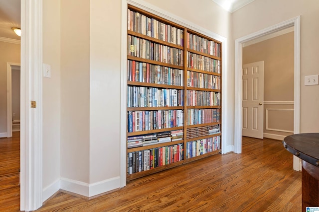 interior space with crown molding, baseboards, and wood finished floors