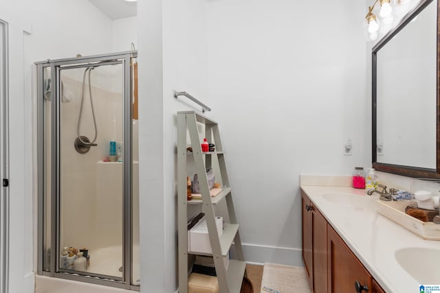 full bath with baseboards, double vanity, a sink, and a shower stall