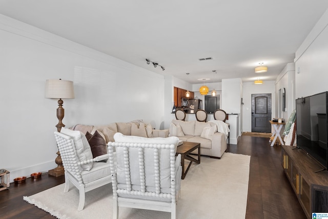 living area featuring dark wood-style flooring, visible vents, and baseboards